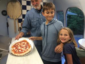 Photo of Darrold, Anthony and Celia in Airstream kitchen with Anthony's pizza